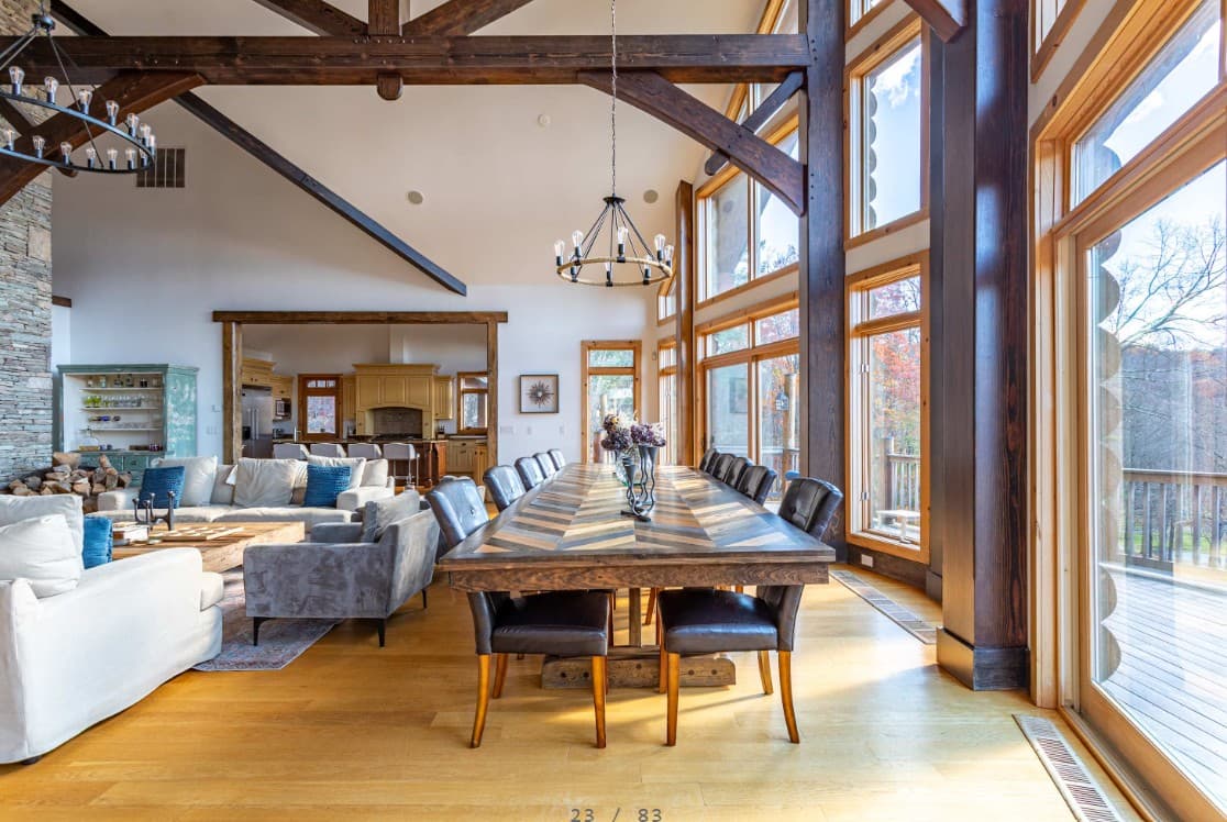 Open great room with long dining table, sofas, and floor-to-ceiling windows