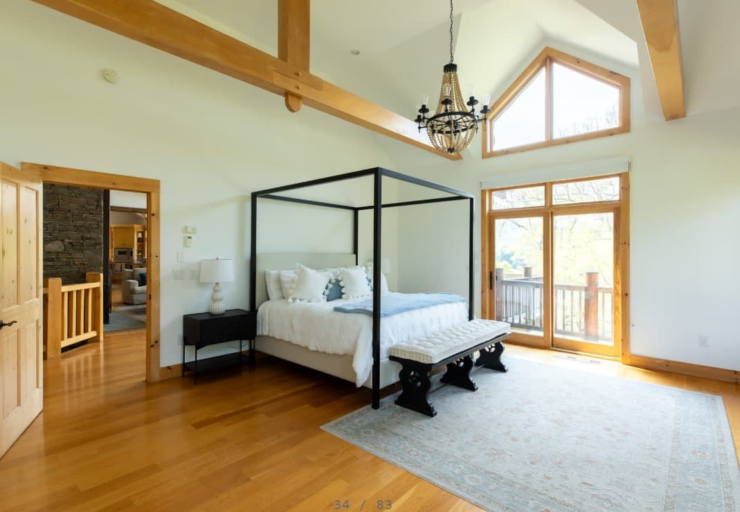 Bright luxury bedroom with four-poster bed and vaulted wood beams