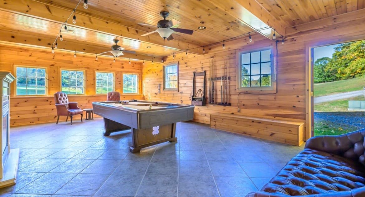 Wood-paneled game room with pool table and warm string lights